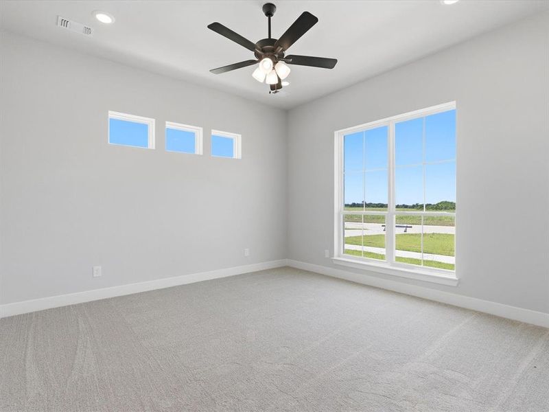 Spacious room featuring a large picture window, three transom windows, light gray carpet, and a ceiling fan with integrated lighting