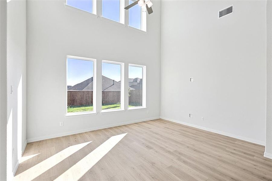 Unfurnished living room with a high ceiling, light wood-type flooring, and ceiling fan