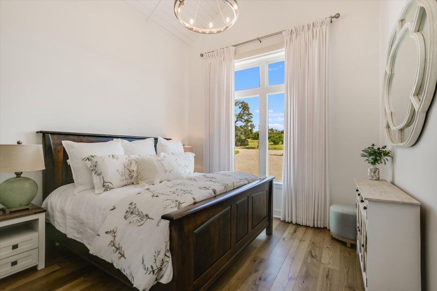 Bedroom featuring wood finished floors, a chandelier, and vaulted ceiling Bedroom featuring wood finished floors, a chandelier, and vaulted ceiling