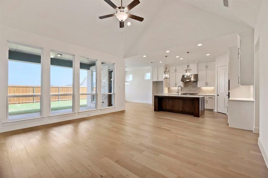 Unfurnished living room with a ceiling fan, lofted ceiling, light wood-style floors, and recessed lighting