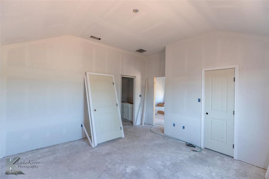Unfurnished bedroom featuring unfinished concrete flooring and vaulted ceiling