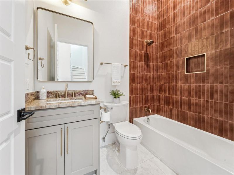 Full bathroom with vanity, tiled shower / bath combo, toilet, and tile patterned flooring