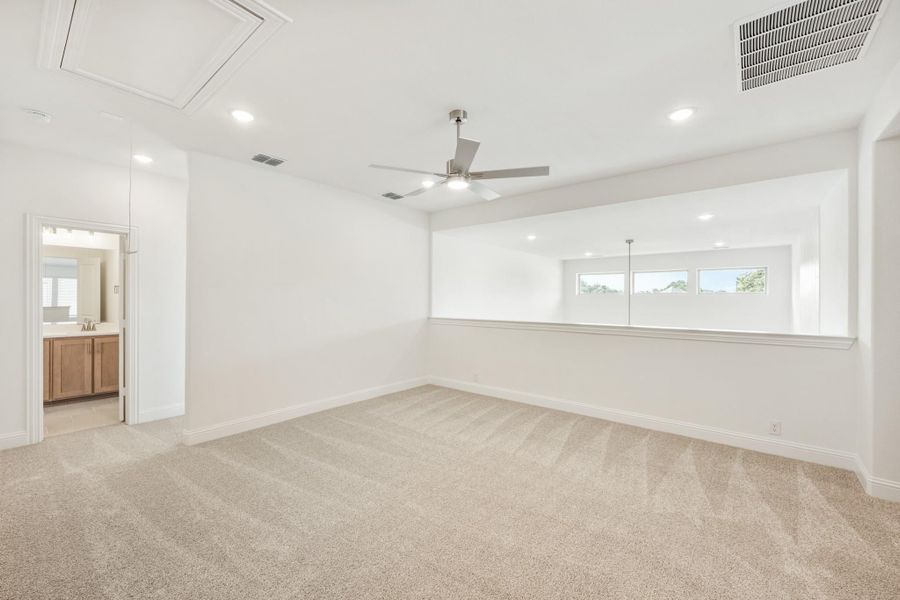 Empty master bedroom with carpet, ceiling fan, recessed lighting, and ensuite bathroom doorway visible