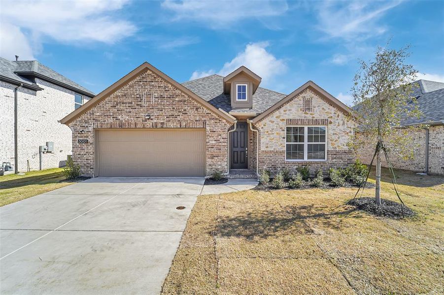 French country home featuring concrete driveway, brick siding, an attached garage, and a shingled roof