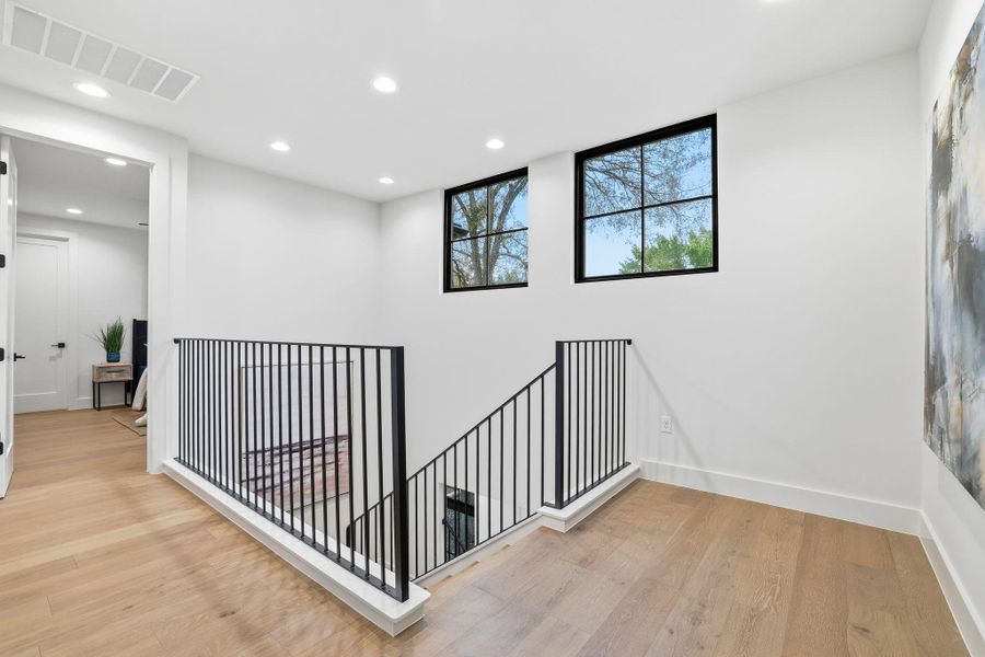 Hallway with recessed lighting, an upstairs landing, and light wood-type flooring