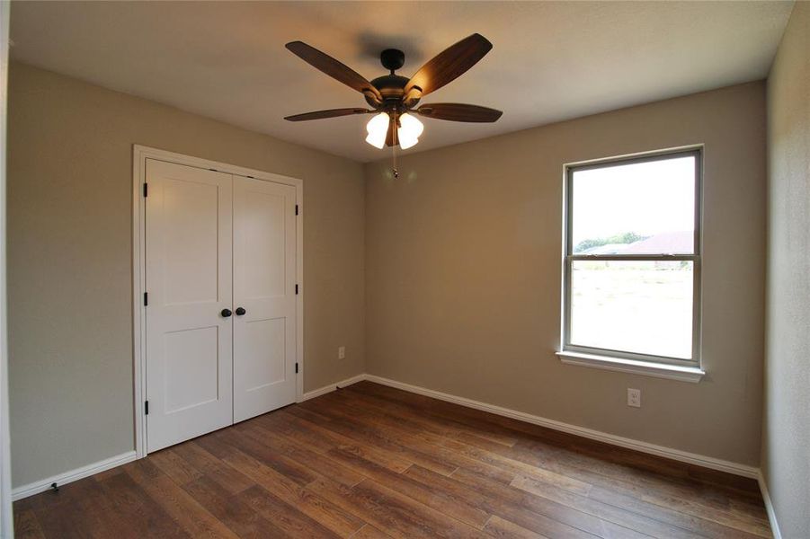 Unfurnished bedroom featuring dark wood-style flooring, a closet, and a ceiling fan