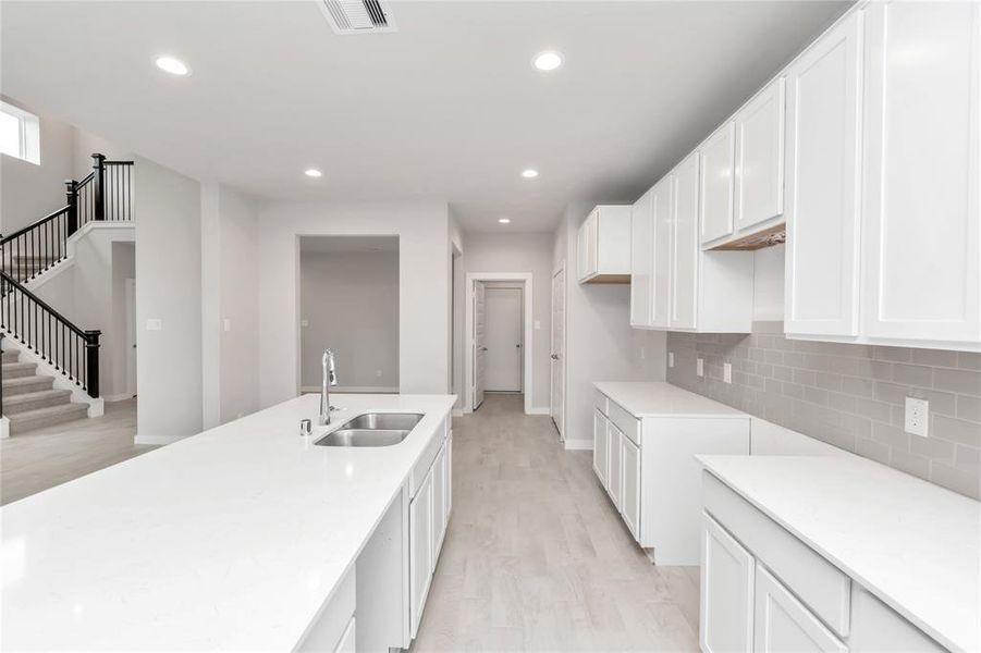 Discover another perspective of this stunning kitchen, generously appointed with an abundance of counter space. Sample photo of completed home with similar floor plan. As-built interior colors and selections may vary