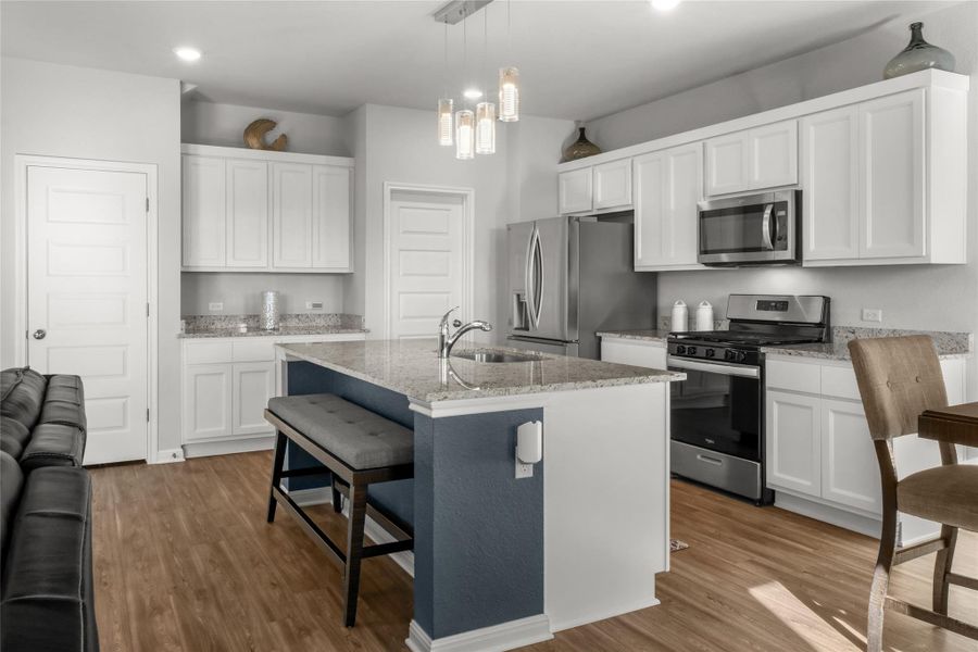Kitchen with stainless steel appliances, a kitchen breakfast bar, light wood-type flooring, light stone countertops, and recessed lighting