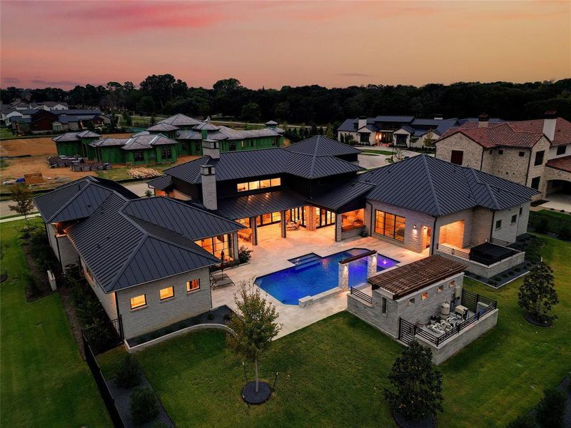 Pool at dusk with a jacuzzi, a patio area, and a yard