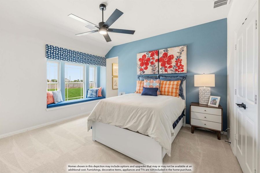 Bedroom with blue accent wall, vaulted ceiling, ceiling fan, and window seat with carpet flooring