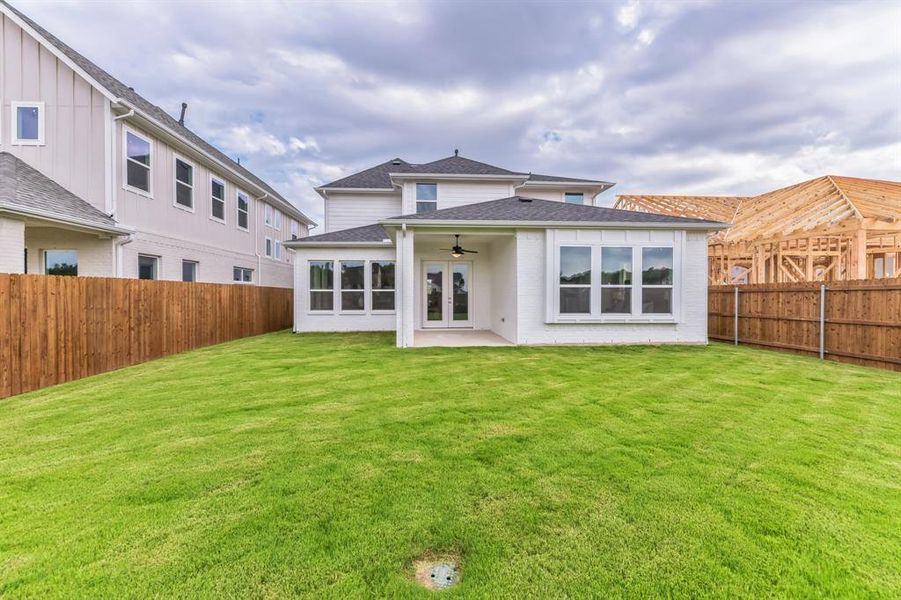 Rear view of house with a patio, ceiling fan, and a lawn