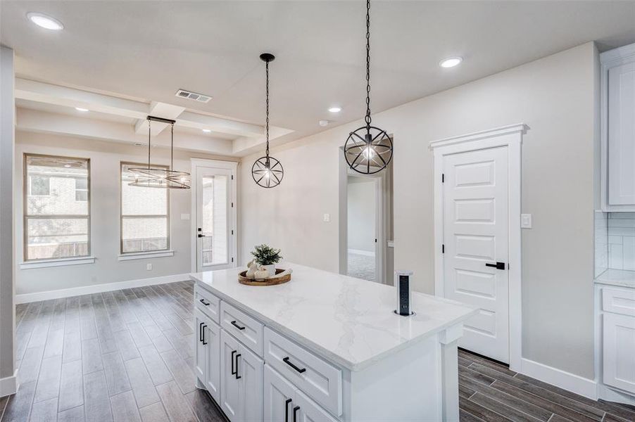 Kitchen with wood tiled floors, white cabinets, a center island, pendant lighting, and recessed lighting