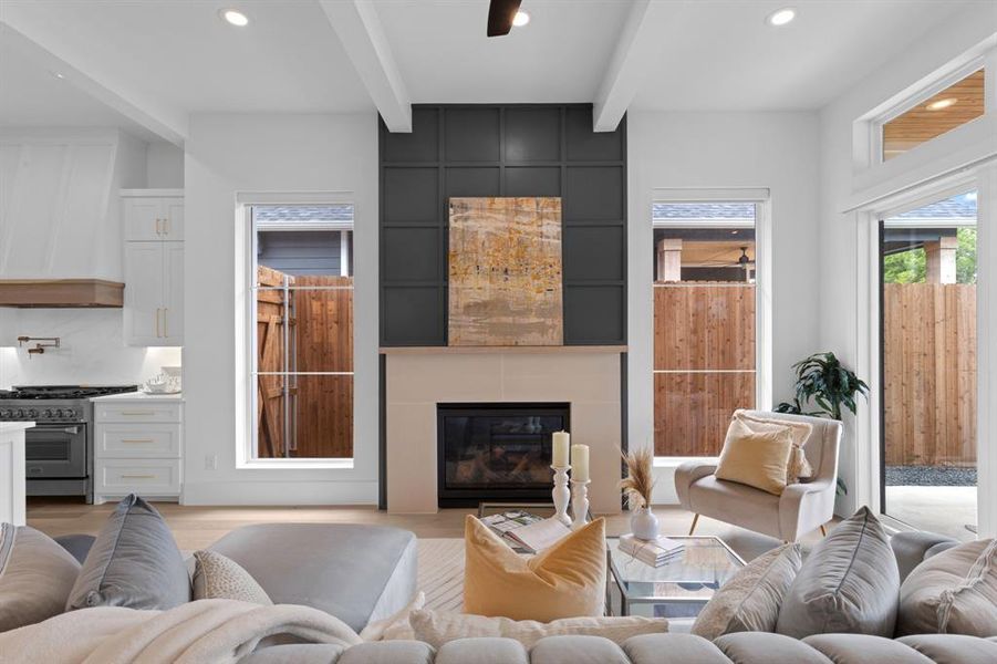 Living room with beam ceiling, a large fireplace, recessed lighting, and light wood-style flooring Living room with beam ceiling, a large fireplace, recessed lighting, and light wood-style flooring