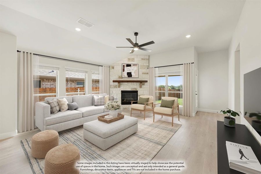 Living room with stone fireplace, ceiling fan, light hardwood floors, and large windows