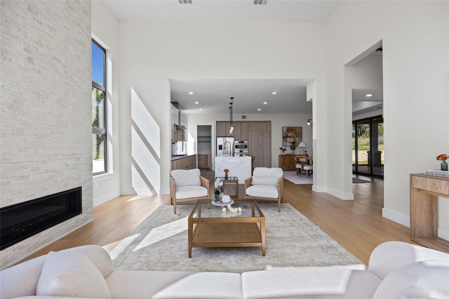 Living room featuring a fireplace, light wood-style flooring, a high ceiling, french doors, and recessed lighting
