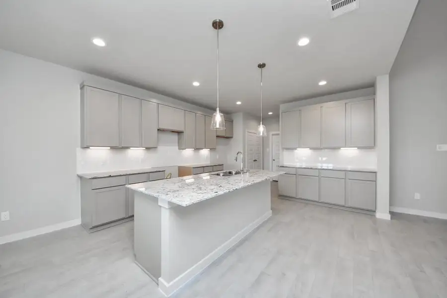 The kitchen is a culinary haven, featuring granite countertops, a tile backsplash, stainless steel appliances, 42” upper cabinets, and undercabinet lighting. Sample photo of completed home with similar floor plan. Actual colors and selections may vary. The kitchen is a culinary haven, featuring granite countertops, a tile backsplash, stainless steel appliances, 42” upper cabinets, and undercabinet lighting. Sample photo of completed home with similar floor plan. Actual colors and selections may vary.