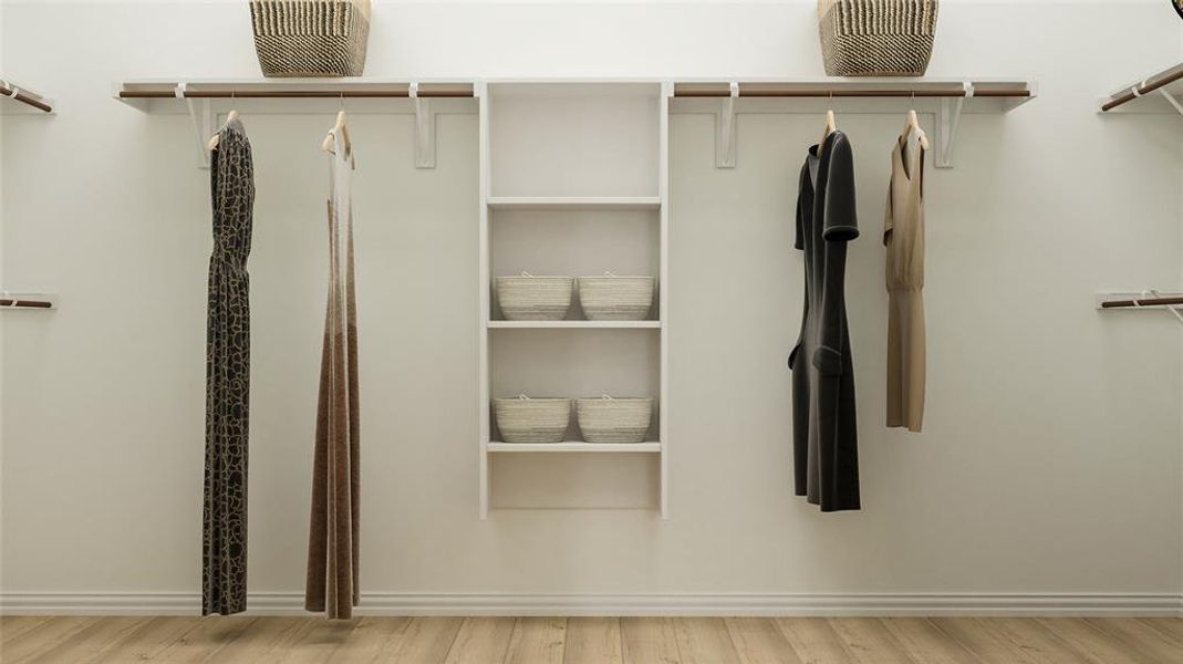 Walk in closet with light hardwood / wood-style flooring