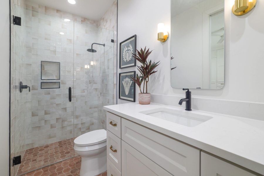 Contemporary bathroom featuring a frameless glass shower enclosure with matte black fixtures, textured wall tiling, and dual shower niches