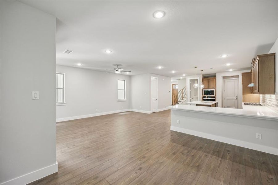 Unfurnished living room featuring ceiling fan and dark hardwood / wood-style flooring