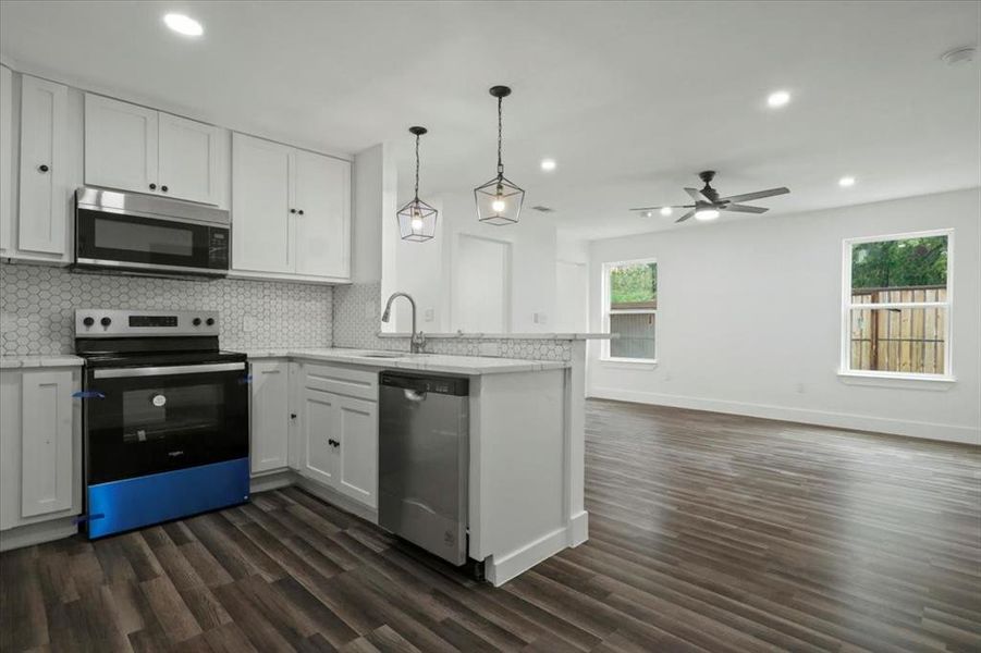 Kitchen featuring ceiling fan, dark hardwood / wood-style floors, appliances with stainless steel finishes, and white cabinetry