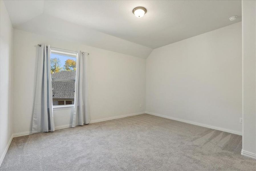 Unfurnished room with light colored carpet and lofted ceiling