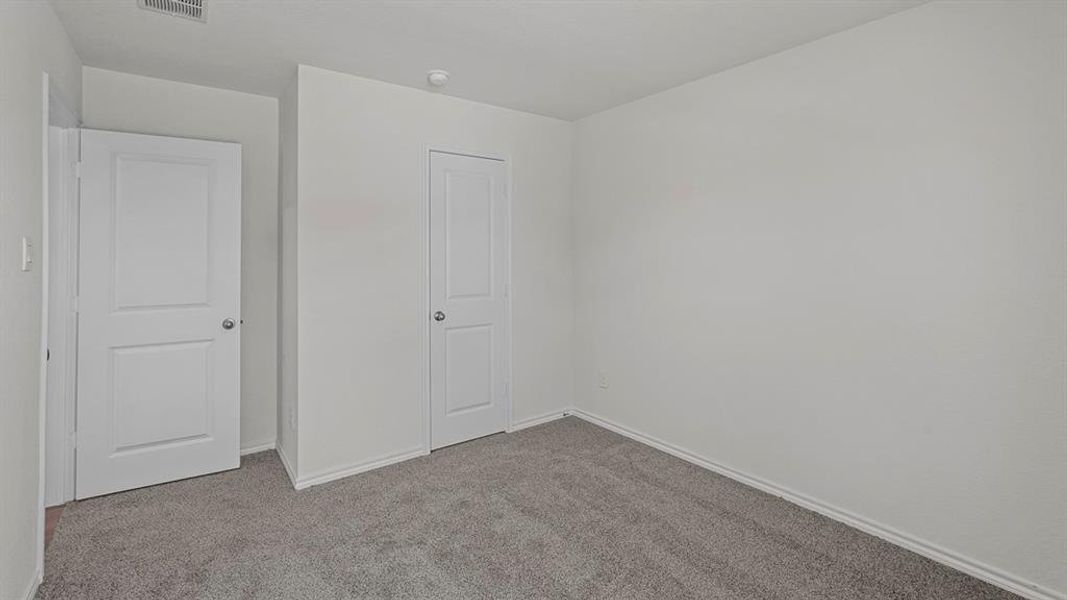Neutral-toned room featuring a soft gray carpet, white walls, and two panel doors with chrome hardware