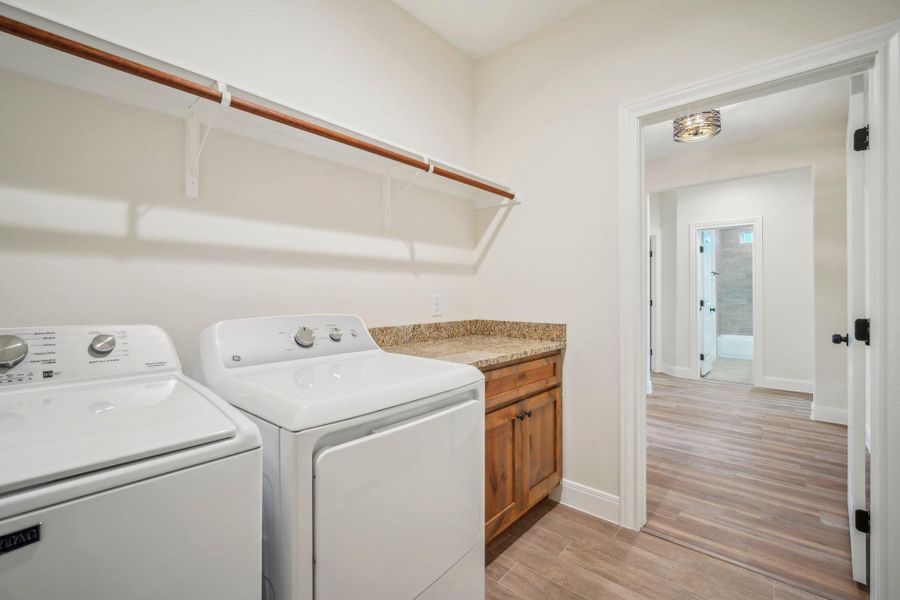 Laundry area with cabinet space, light wood-style floors, independent washer and dryer, and baseboards