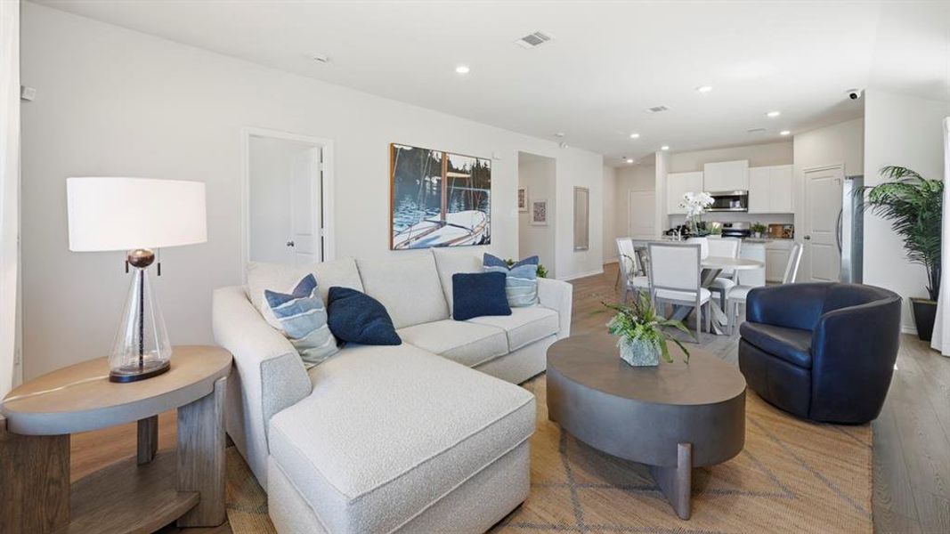 Open-concept living area featuring light-colored walls, recessed lighting, and wood-style flooring