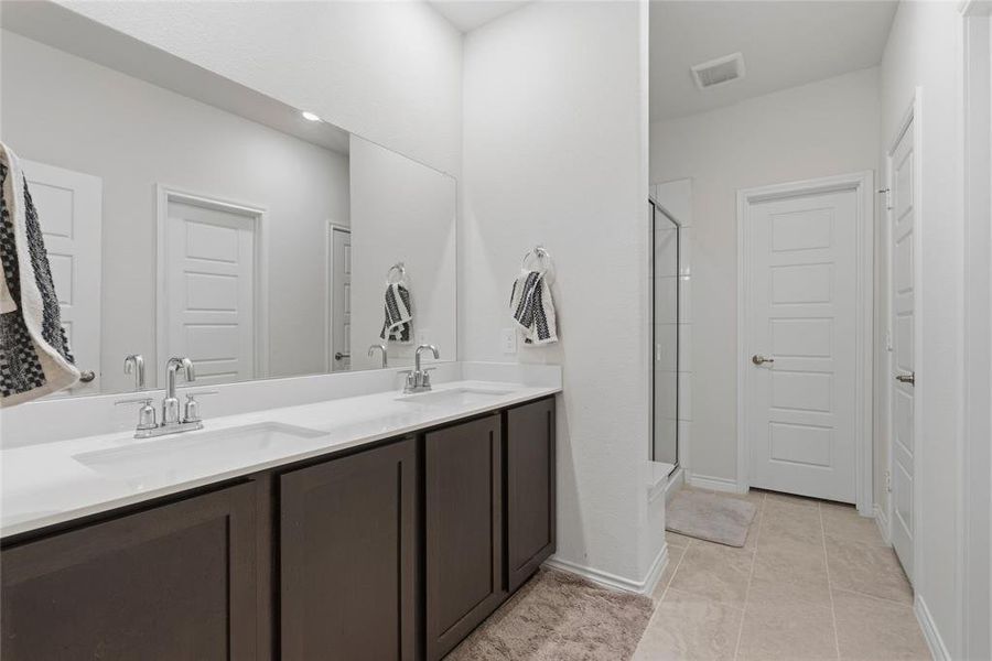 Dual vanity with integrated sinks, white countertops, and dark cabinetry