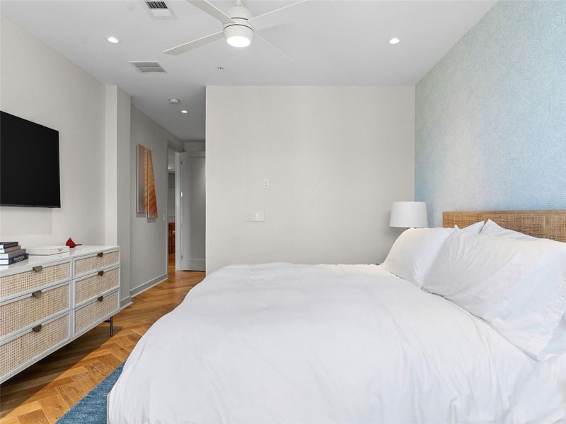 Herringbone wood-finish flooring, recessed lighting, and a contemporary ceiling fan Herringbone wood-finish flooring, recessed lighting, and a contemporary ceiling fan