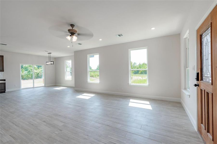 Unfurnished living room featuring ceiling fan, light hardwood / wood-style floors, and a healthy amount of sunlight