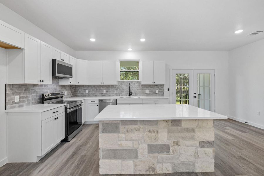 An inviting kitchen with pristine counters, modern appliances, and a captivating stone-clad island. An inviting kitchen with pristine counters, modern appliances, and a captivating stone-clad island.