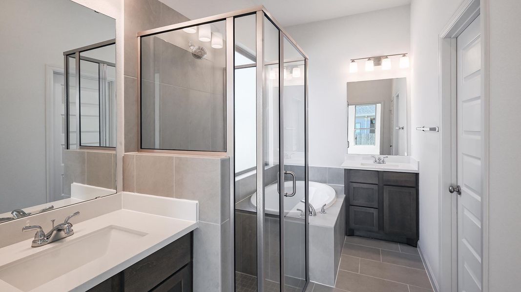 Bathroom with a stall shower, a bath, two vanities, and light tile patterned flooring