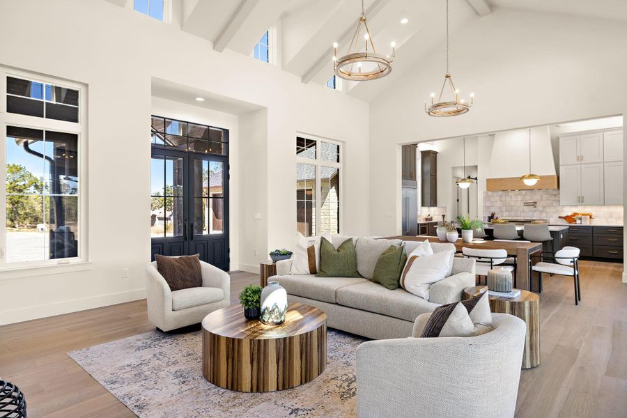 Living room featuring a chandelier, high vaulted ceiling, baseboards, light wood finished floors, and beamed ceiling