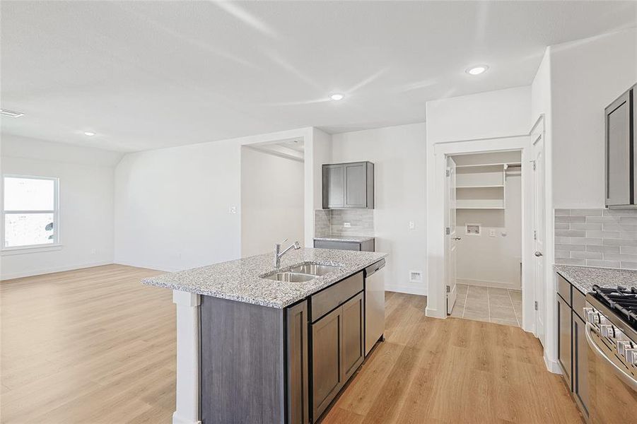 Kitchen featuring sink, light hardwood / wood-style flooring, light stone countertops, tasteful backsplash, and stainless steel appliances