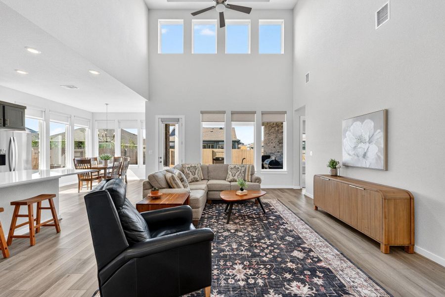 Large 2-story living room with ceiling fan. Open to the dining room and kitchen.