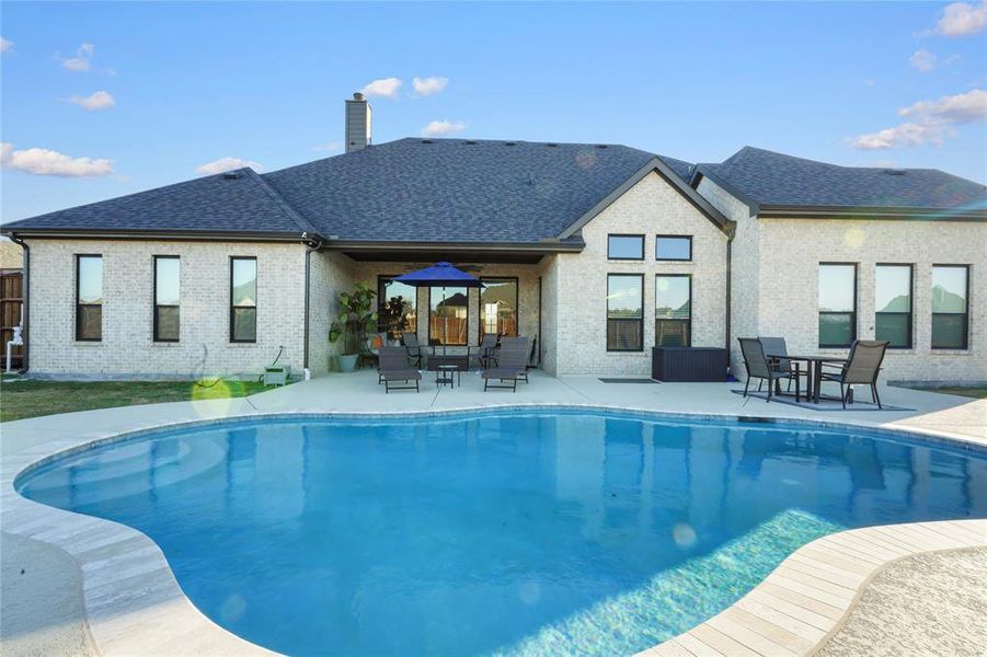 Back of property featuring a patio area, an outdoor pool, a chimney, a shingled roof, and brick siding Back of property featuring a patio area, an outdoor pool, a chimney, a shingled roof, and brick siding