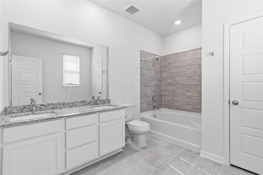 Luxurious primary suite bath boasts a large double sink vanity topped with elegant countertops and tub/shower combination with tile surround. Luxurious primary suite bath boasts a large double sink vanity topped with elegant countertops and tub/shower combination with tile surround.