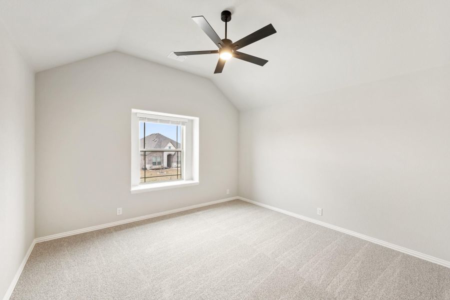 Empty bedroom with vaulted ceiling, black ceiling fan, carpet flooring, and single window Empty bedroom with vaulted ceiling, black ceiling fan, carpet flooring, and single window