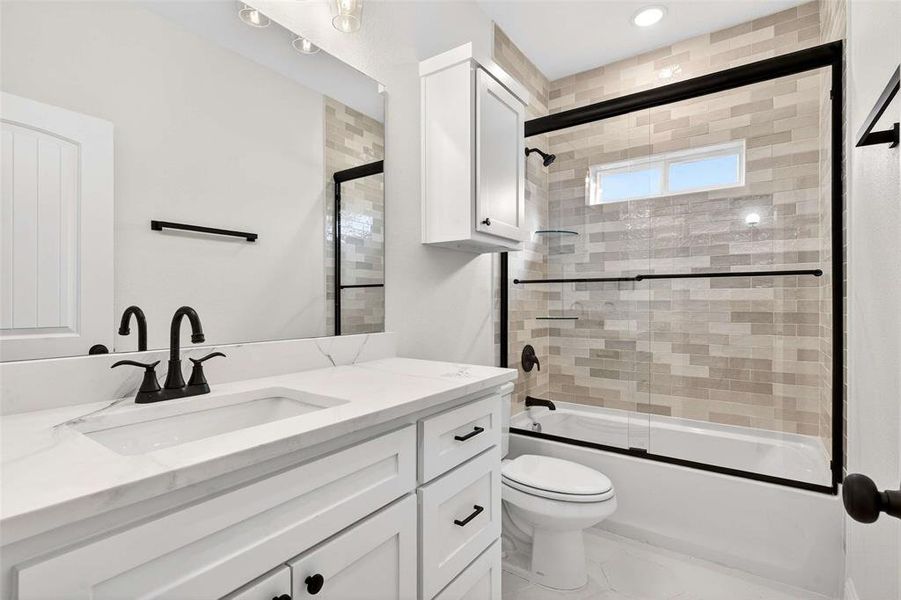 Bathroom with bath / shower combo with glass door and vanity