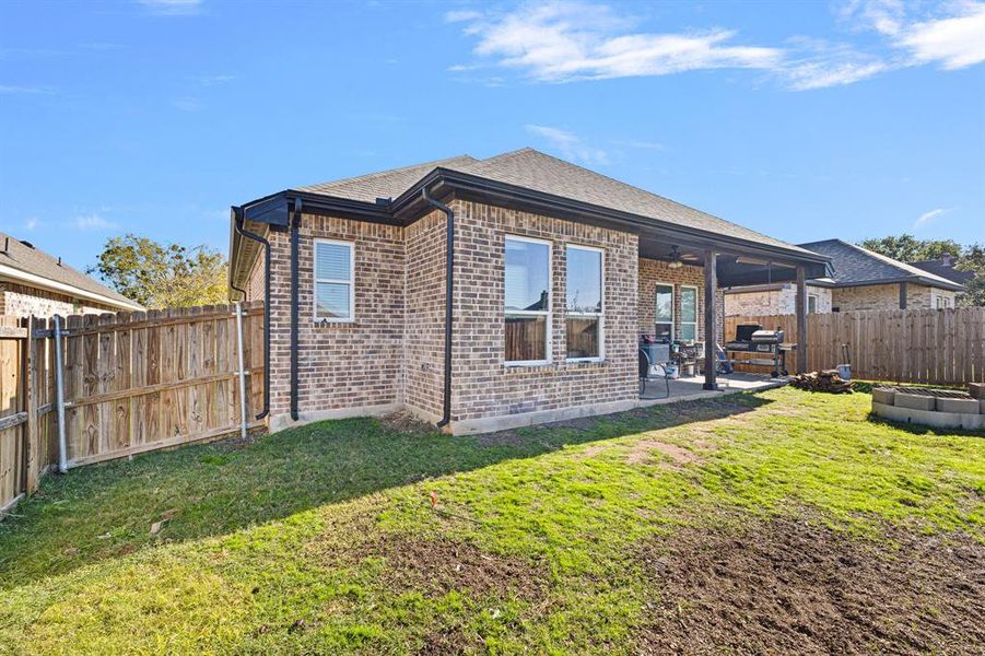 Back of property featuring ceiling fan, a yard, and a patio