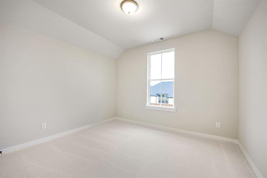 Empty room with lofted ceiling and light carpet