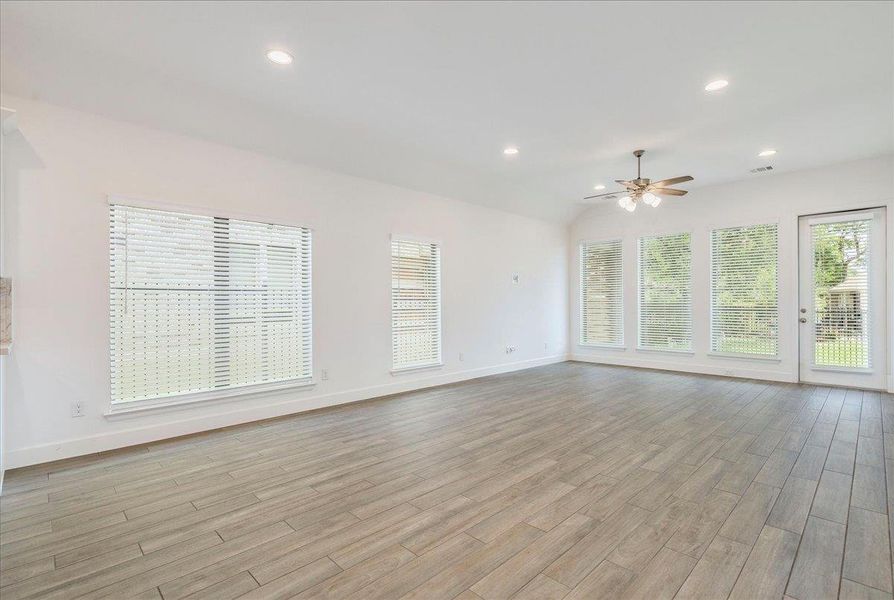 Spacious living area featuring light-colored tile flooring, white walls, and recessed lighting