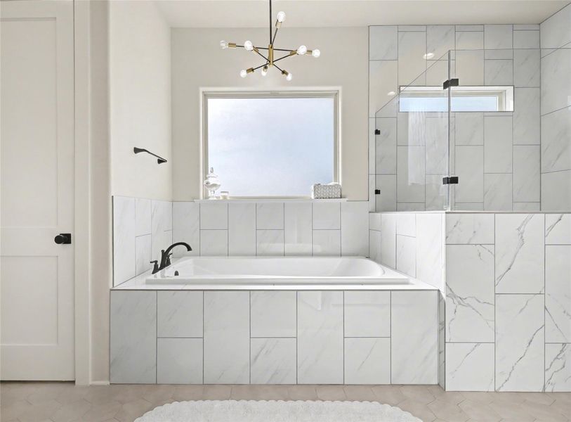 Primary bathroom featuring a shower stall, a bath, and a chandelier