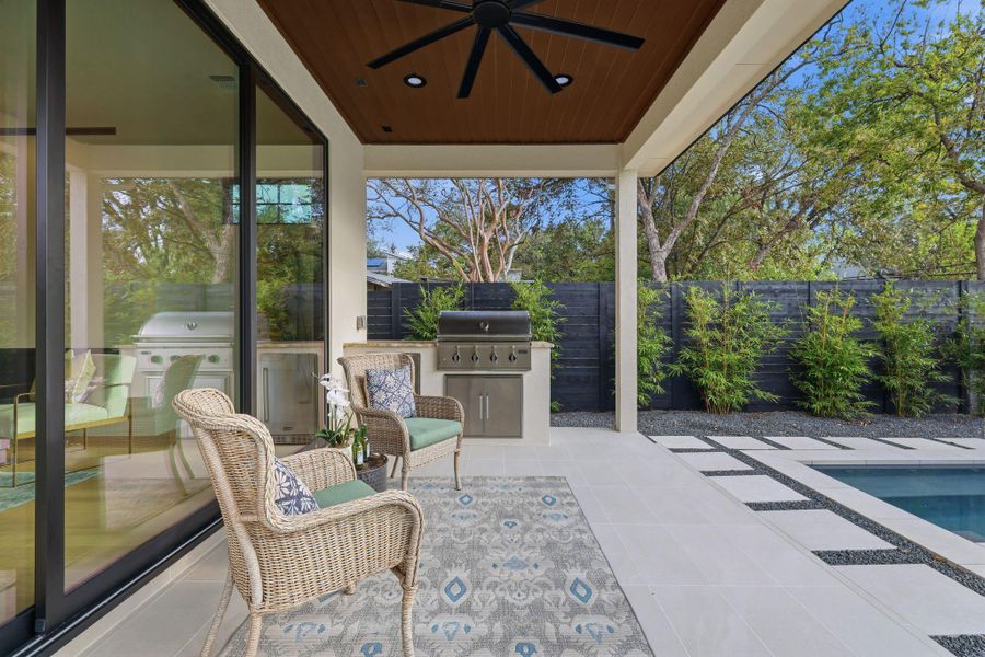 Fenced backyard with exterior kitchen, a patio, and a ceiling fan