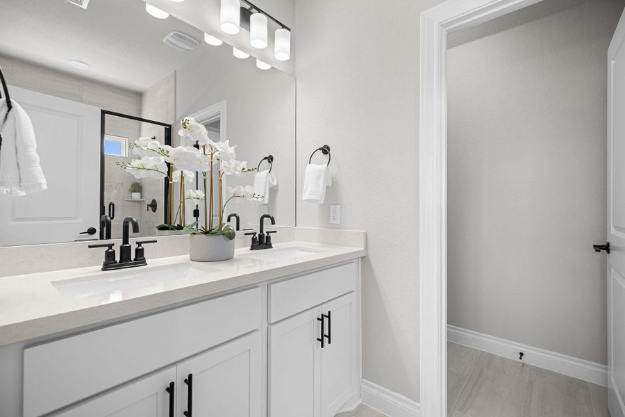 Full bath featuring double vanity and a shower with door