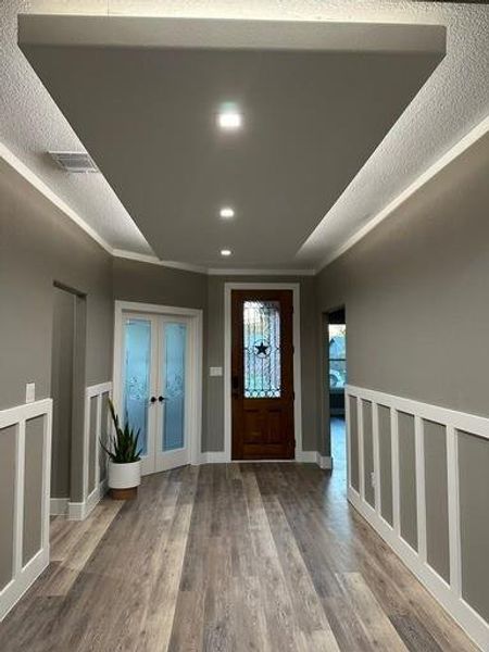 Foyer entrance featuring a textured ceiling, crown molding, hardwood / wood-style floors, and french doors