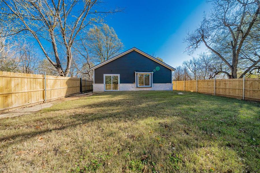 Rear view of house featuring a fenced backyard and brick siding