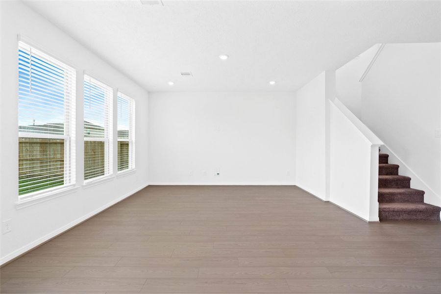 This bright and airy Great Room offers a spacious layout ideal for both relaxing evenings and lively gatherings. Designed for comfort and connection, it features Bandera Earthy Taupe vinyl plank flooring, large windows with blinds, high ceilings, recessed lighting, and seamless access to the stunning kitchen and dining—perfect for everyday living and entertaining alike.