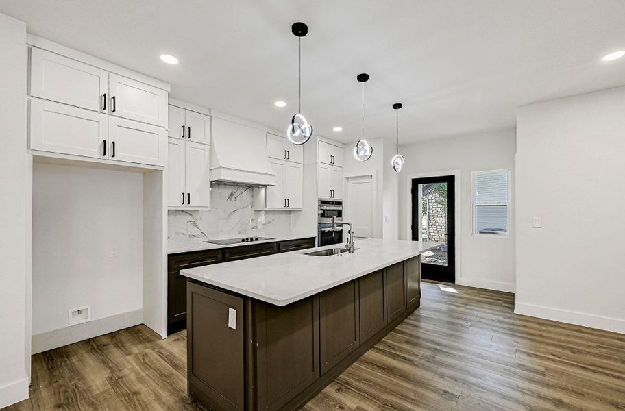 Kitchen with white cabinets, backsplash, hanging light fixtures, dark wood-style floors, and dark brown cabinetry